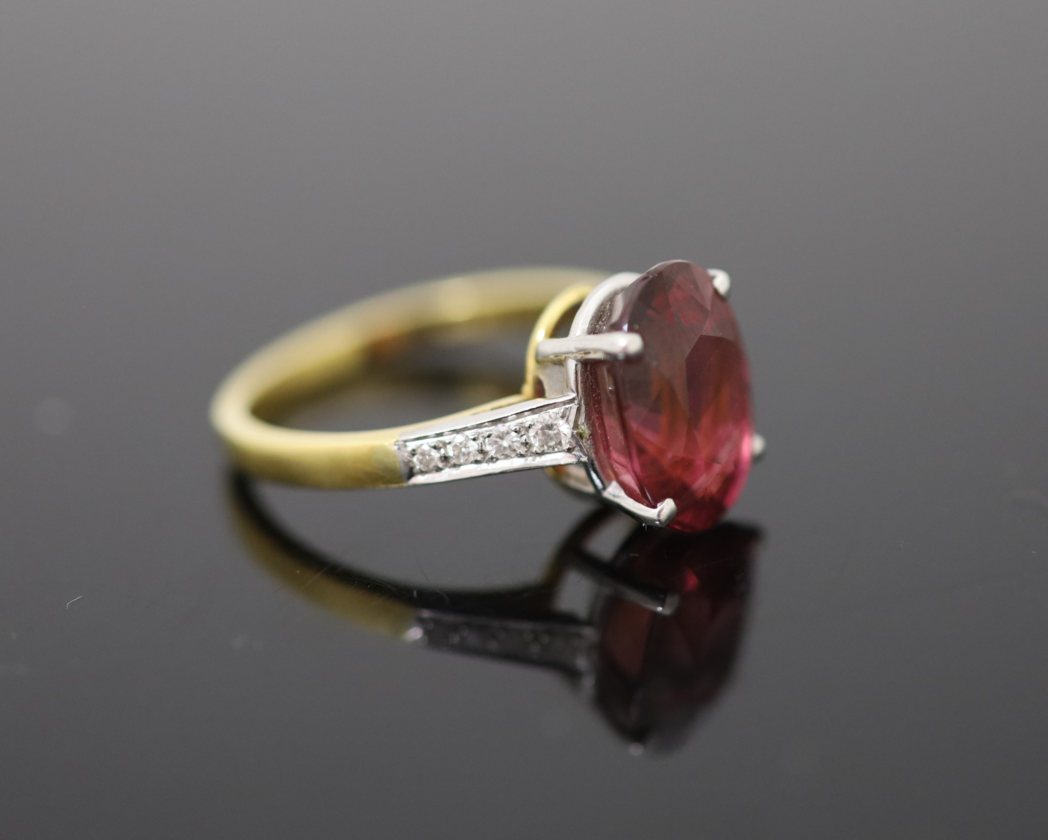 A modern 18ct gold and oval deep pink tourmaline ring, with diamond set shoulders